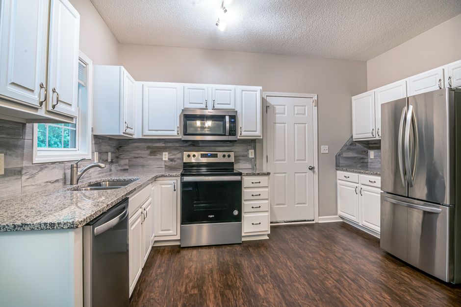 Bright modern kitchen featuring white cabinets and stainless steel appliances.